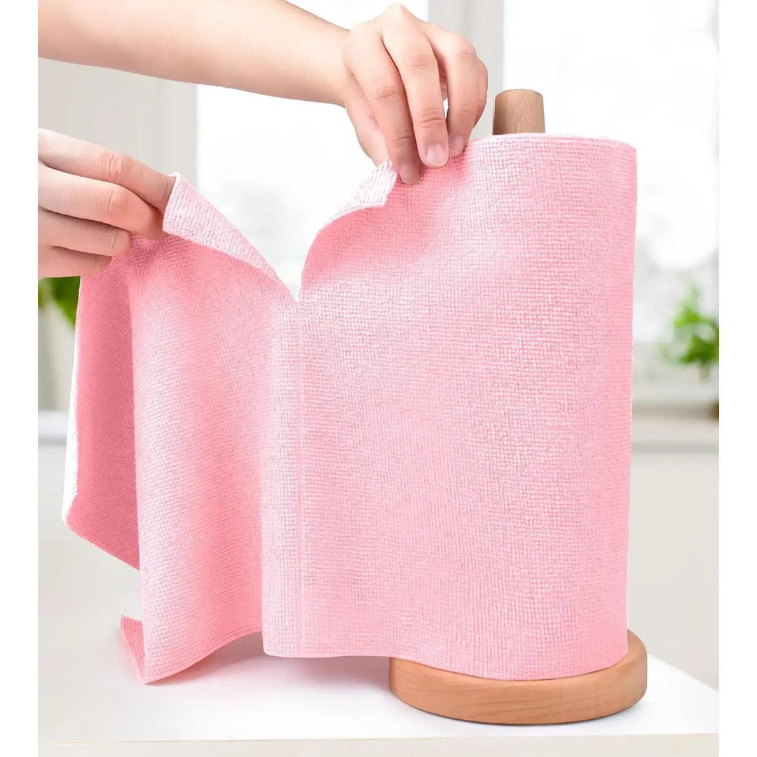 Hands pulling out a Reusable Microfiber Cleaning Cloths from a roll on a wooden holder.
