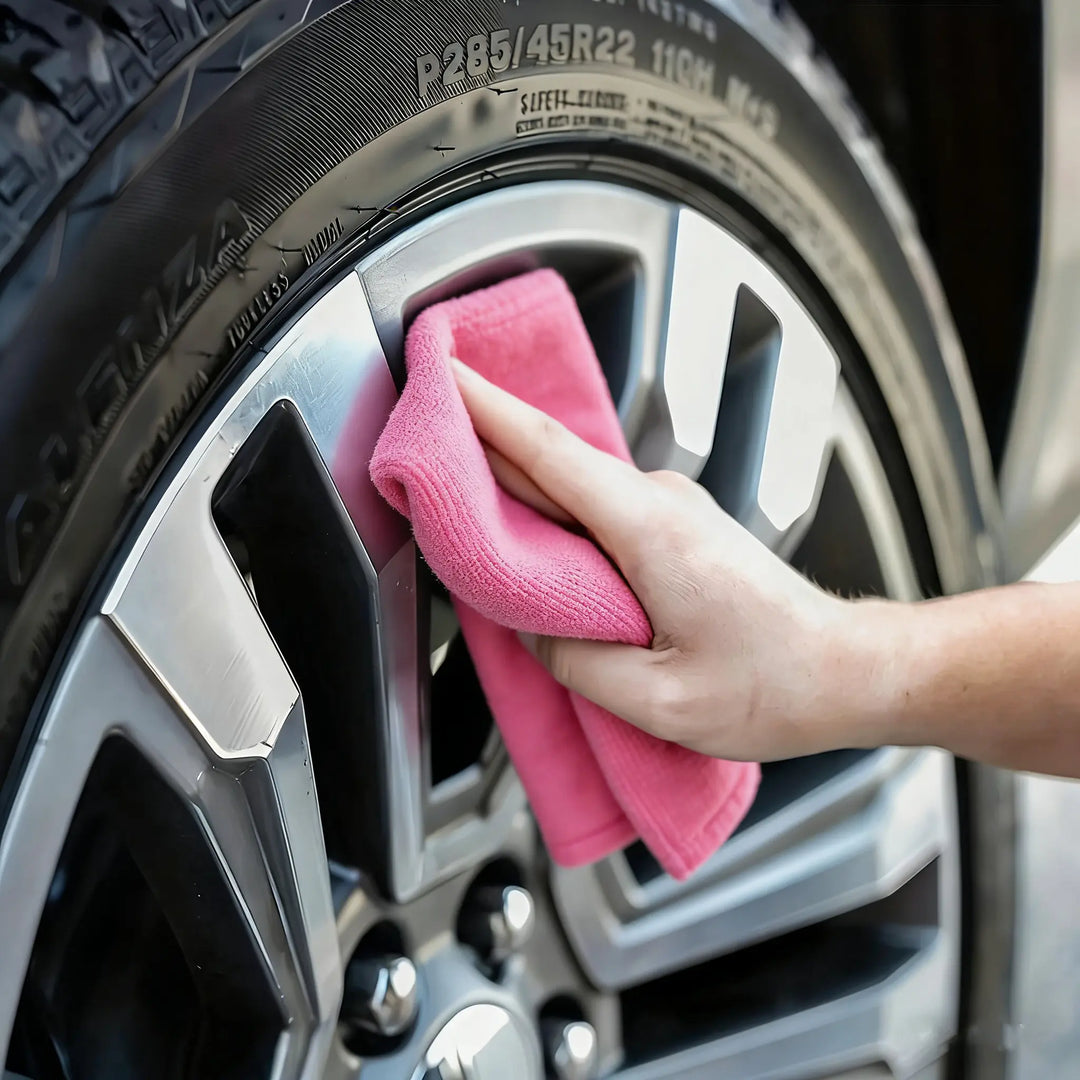 Person cleaning a car wheel using Reusable Microfiber Cleaning Cloths for a streak-free finish.