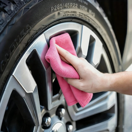 Person cleaning a car wheel using Reusable Microfiber Cleaning Cloths for a streak-free finish.