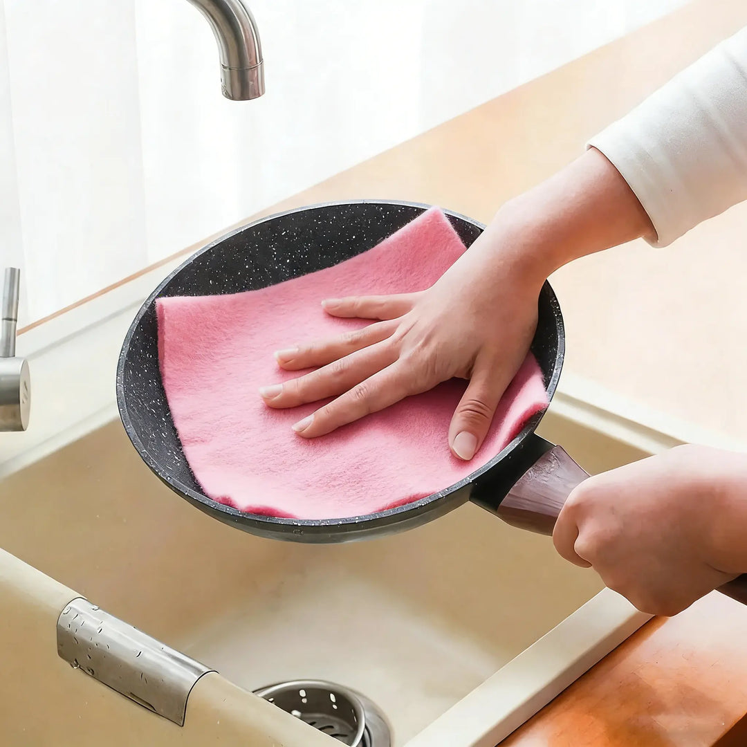 Person using Reusable Microfiber Cleaning Cloths to clean a frying pan in the kitchen sink.